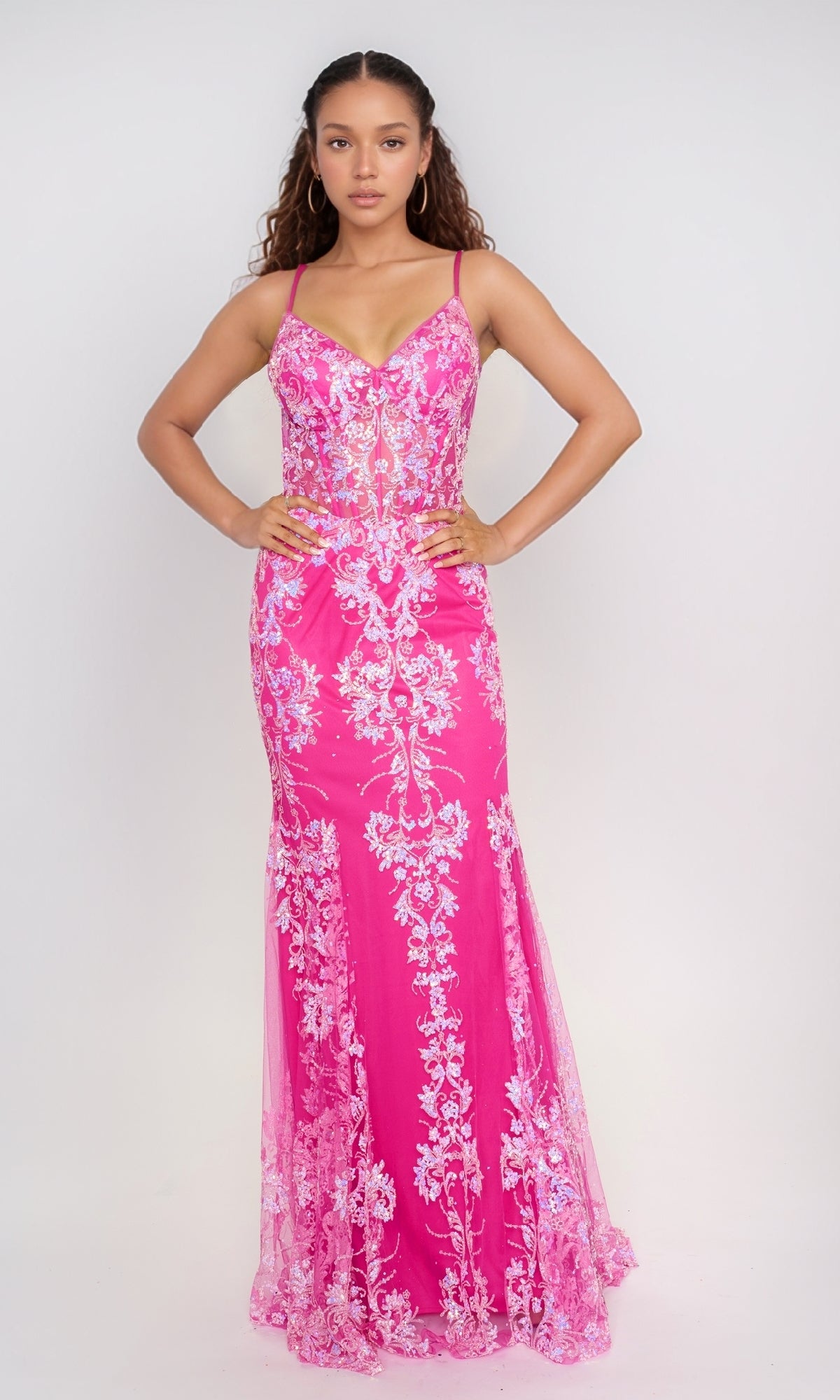 A woman faces forward in the Nina Canacci 1562 long formal dress, a pink fitted mermaid gown with white floral embroidery and thin straps, standing against a plain light background.